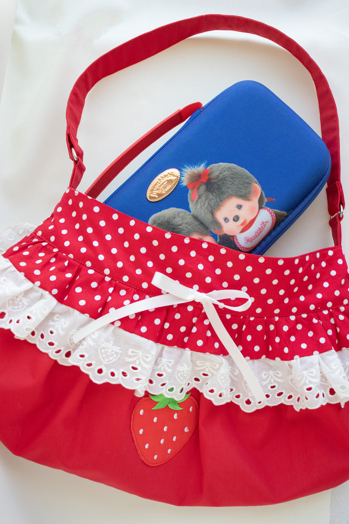 Red fabric shoulder bag with white polka dots, white lace trim, a strawberry applique, and a blue zippered pouch inside.